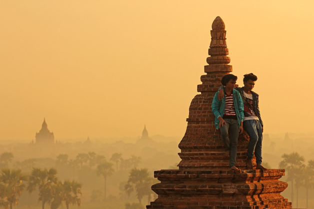 Myanmar young locals watch the sunrise from the top of a pagoda at Bagan